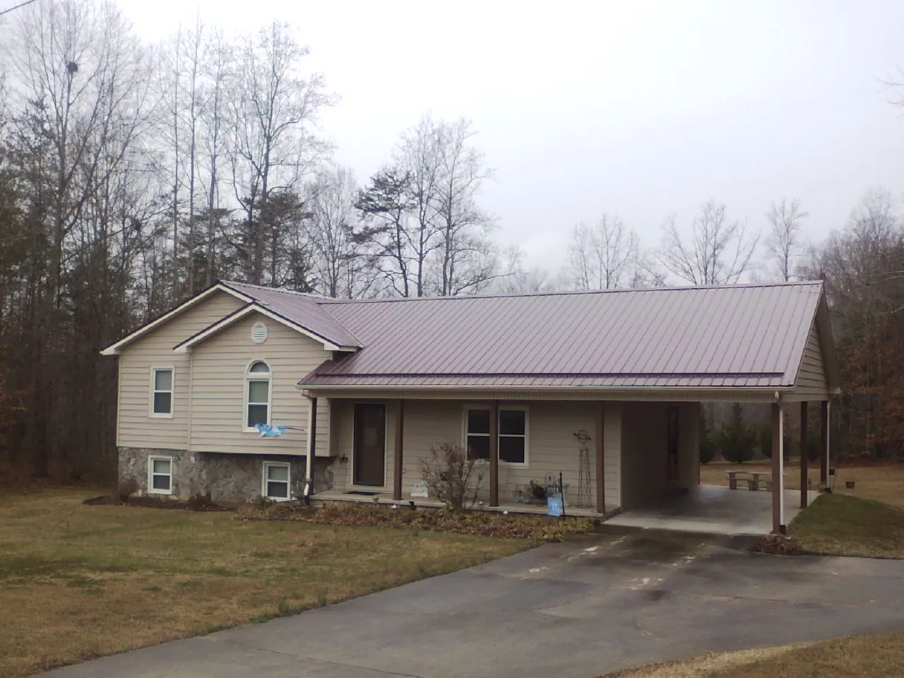 Burgundy metal roof on a tan split level home with an attached carport in Castle Creek