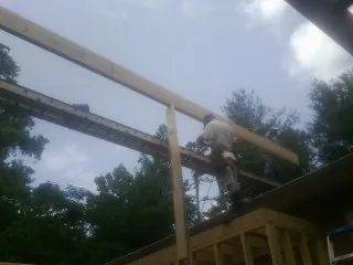 Carpenter setting a ridge beam over a new addition frame — Ice Dam Removal by Roofing Brothers in Castle Creek