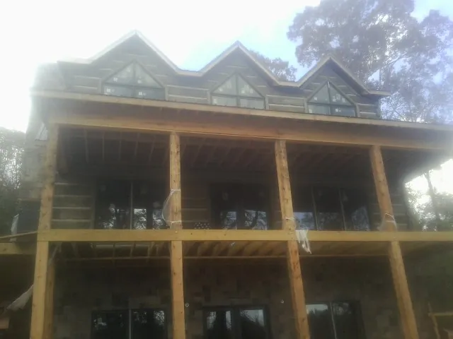 Dormers and porch framing on a large log home under construction — Roof Coating work by our crew in Castle Creek