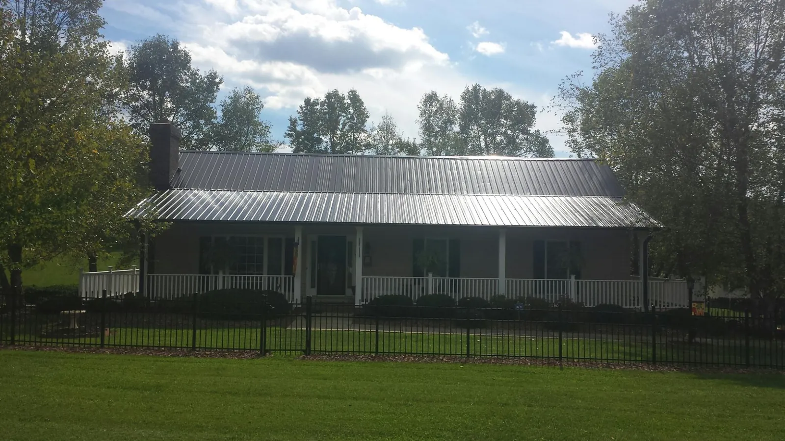 Gray metal roof on a brick ranch with a full width front porch — Gutter Guard Installation work by our crew in Castle Creek