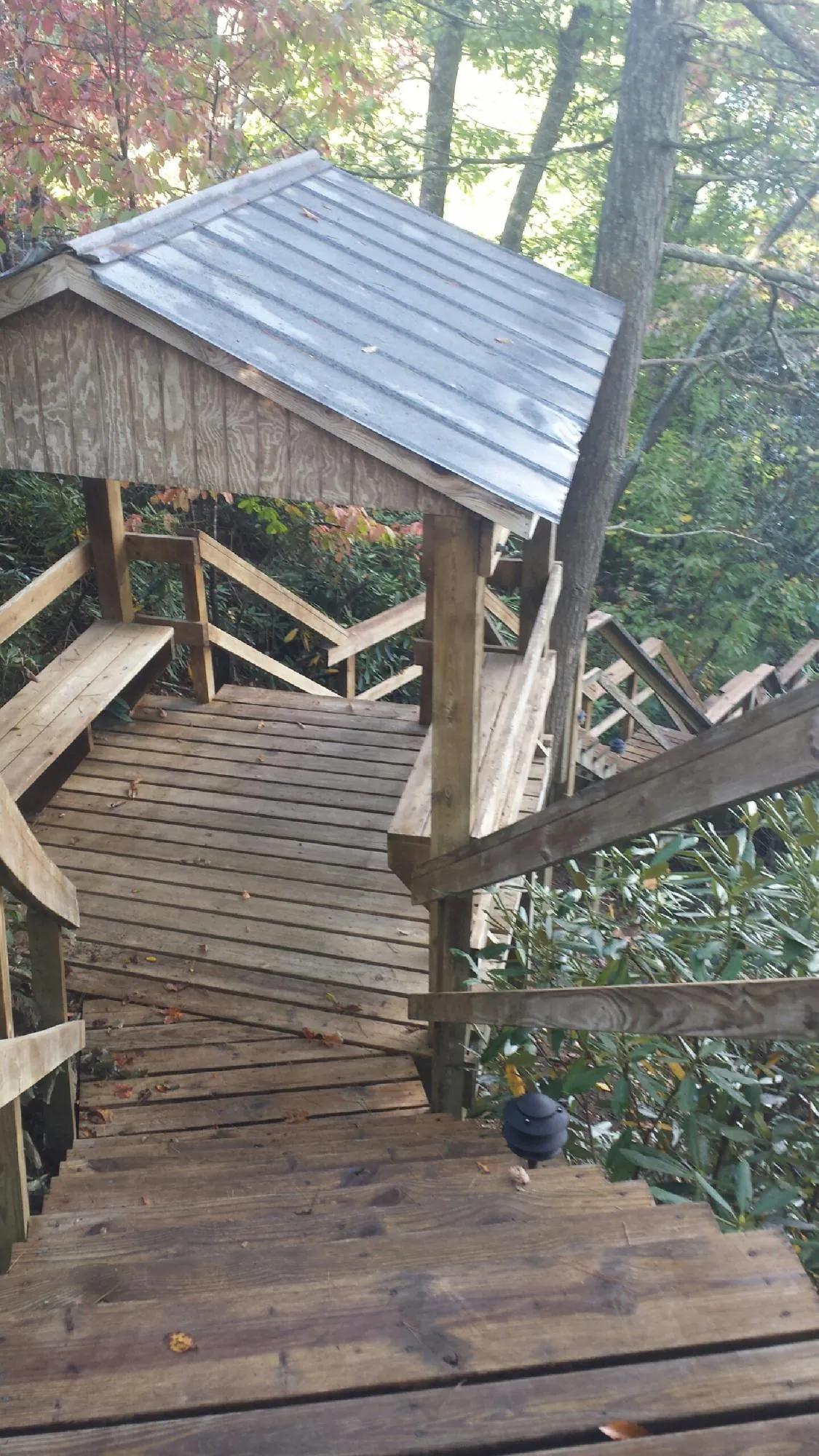Metal roofed shelter over wooden steps on a wooded walkway — Skylight Repair & Installation work by our crew in Castle Creek