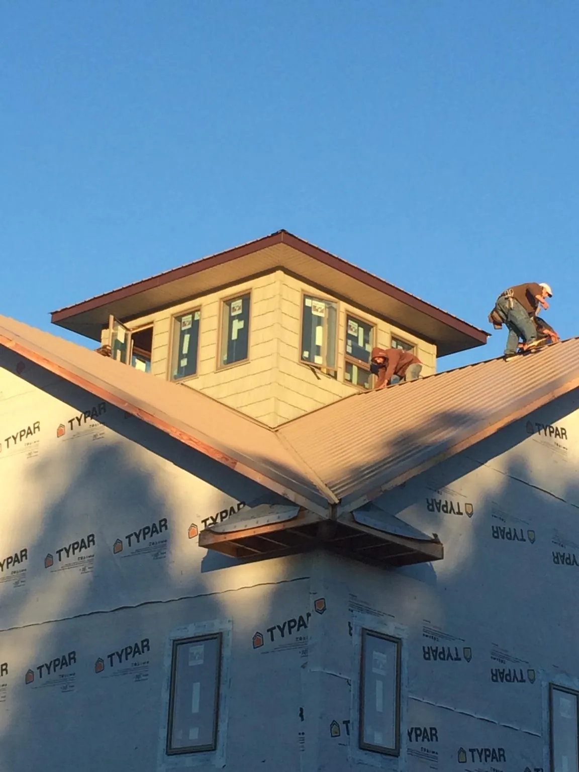 Roofers working around a rooftop cupola on a new metal roof at sunset — Roof Waterproofing in Castle Creek by Roofing Brothers